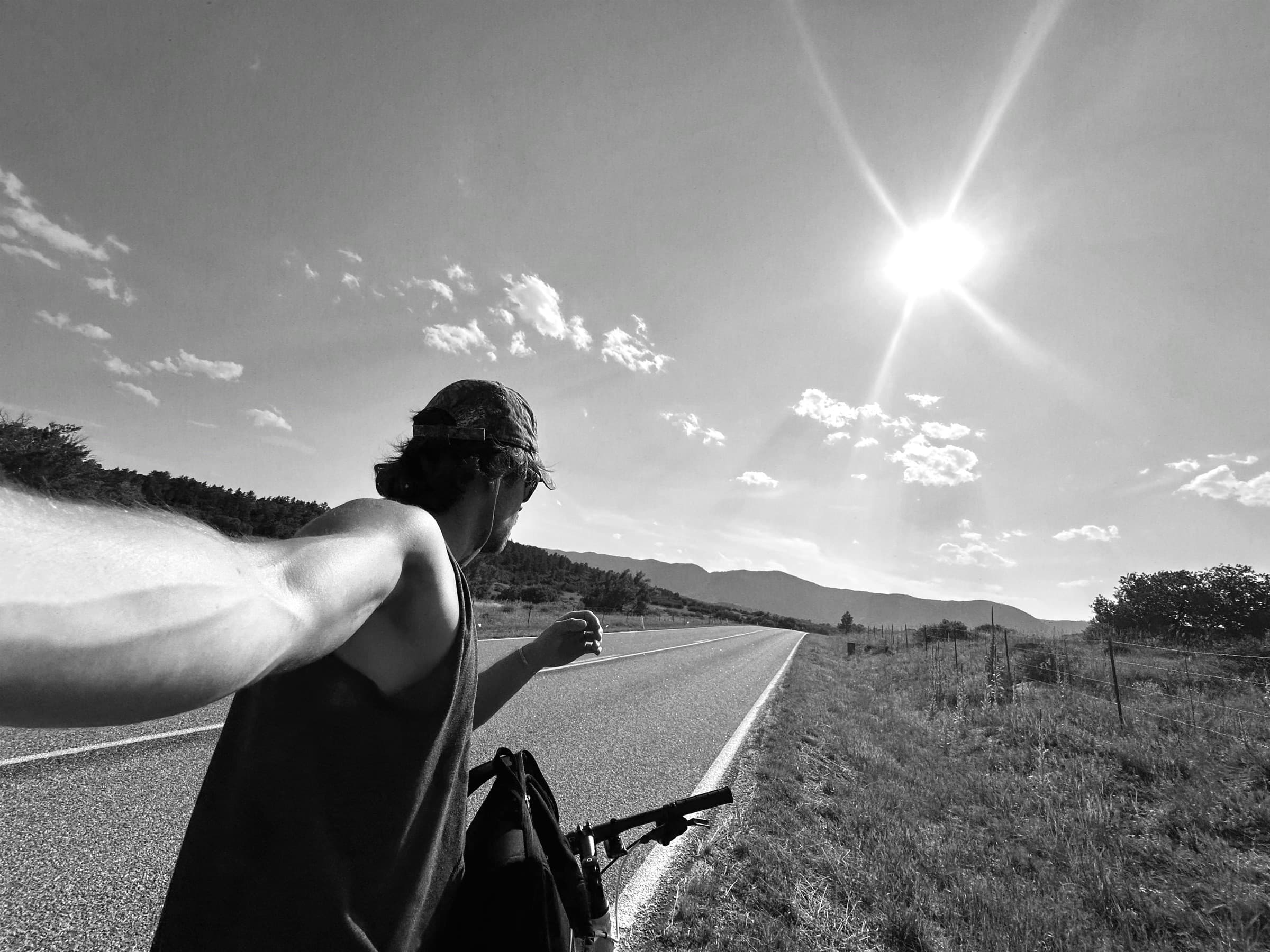 Cyclist taking a selfie on an open Colorado highway under the sun