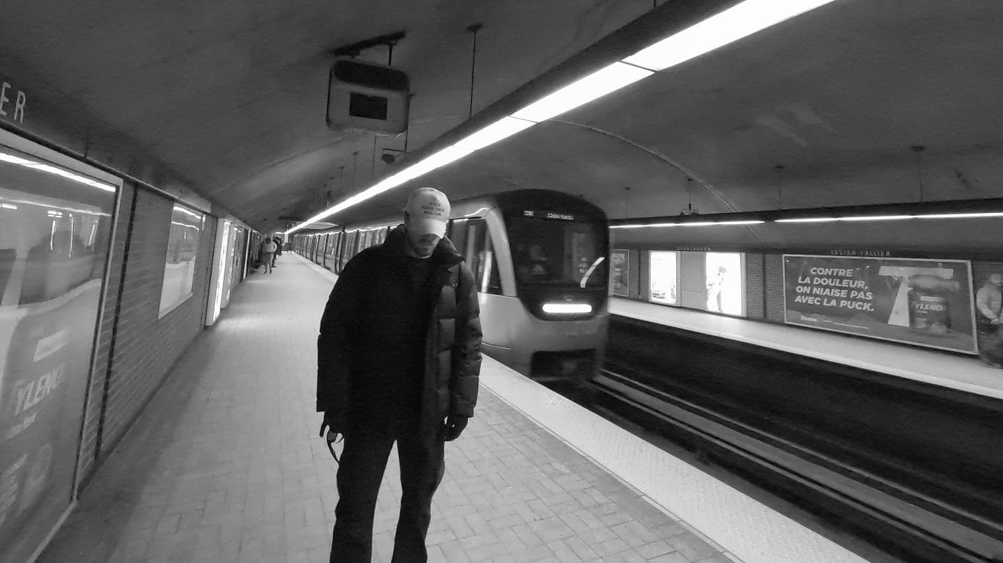 Man in a winter coat on a Montreal metro platform as a train arrives