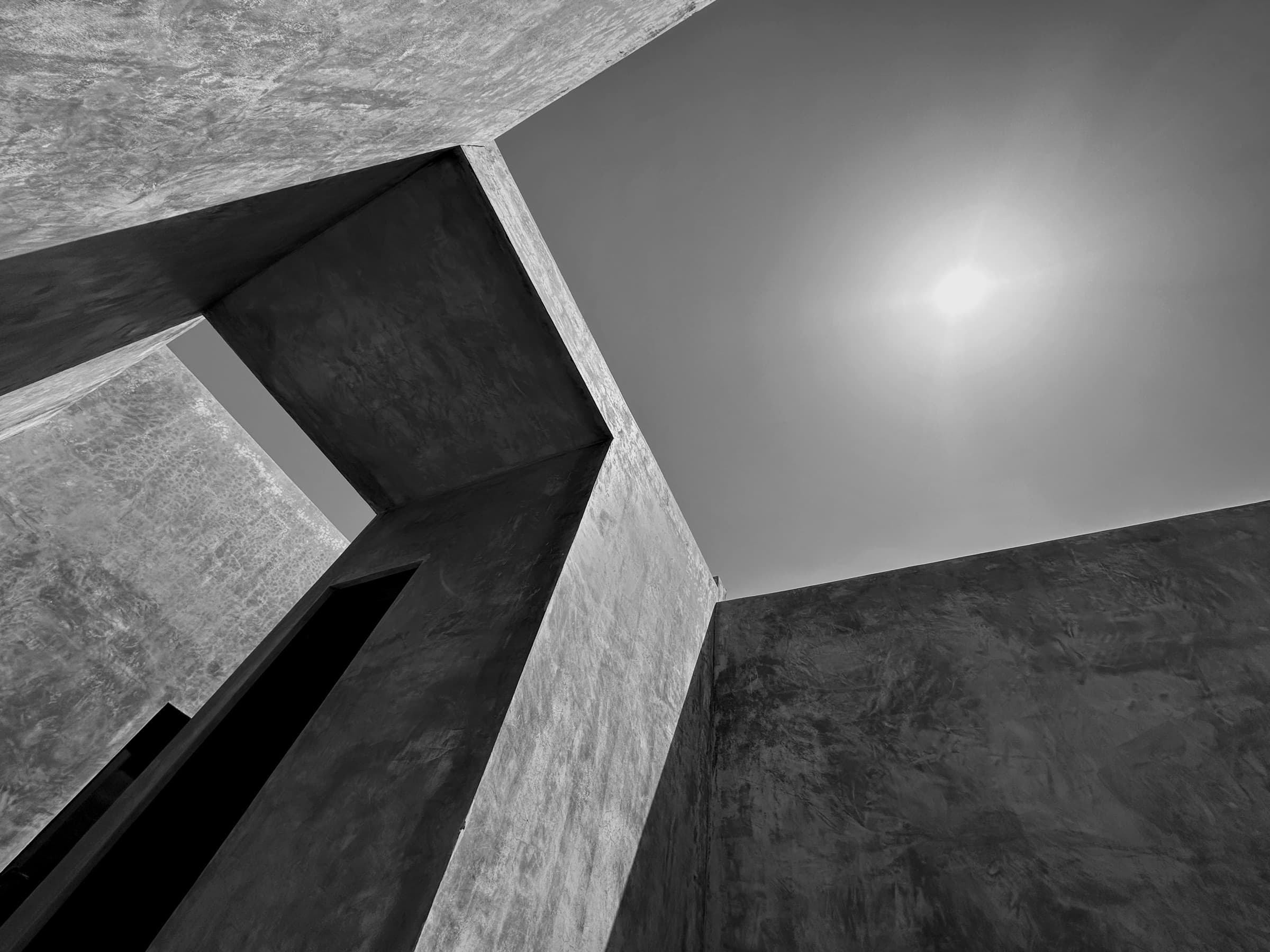 Angular concrete walls framing the sun in Tulum